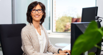 Dunkelhaarige Frau mit Brille am Computer sitzend