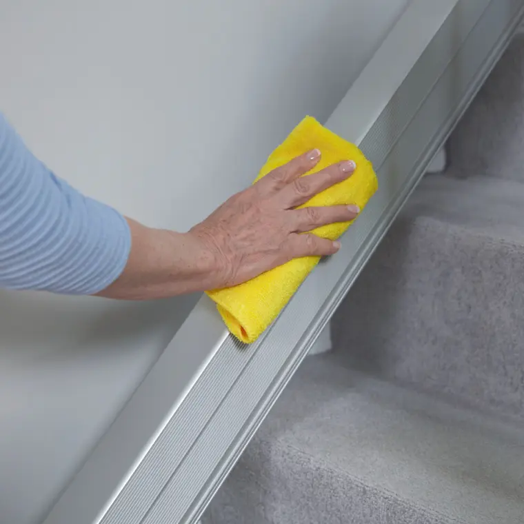 faq-reinigung.png Frau wischt Treppenlift-Schiene mit einem Tuch ab