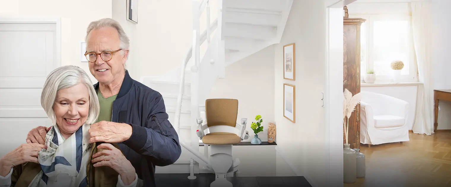 headerstart_neu_schatten_klein.jpg Lächelndes älteres Paar vor einem Treppenlift