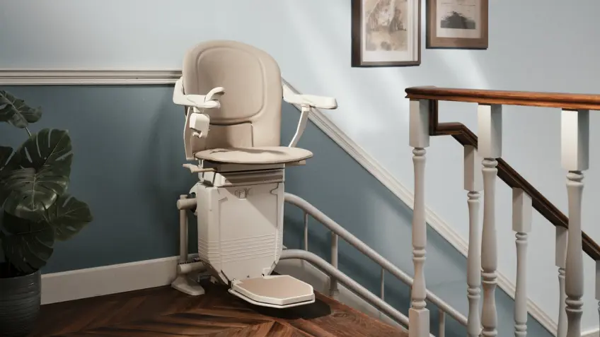 markenteaser-lifta.png Beiger Treppenlift von Lifta am oberen Ende einer Treppe vor hellblauer Wand