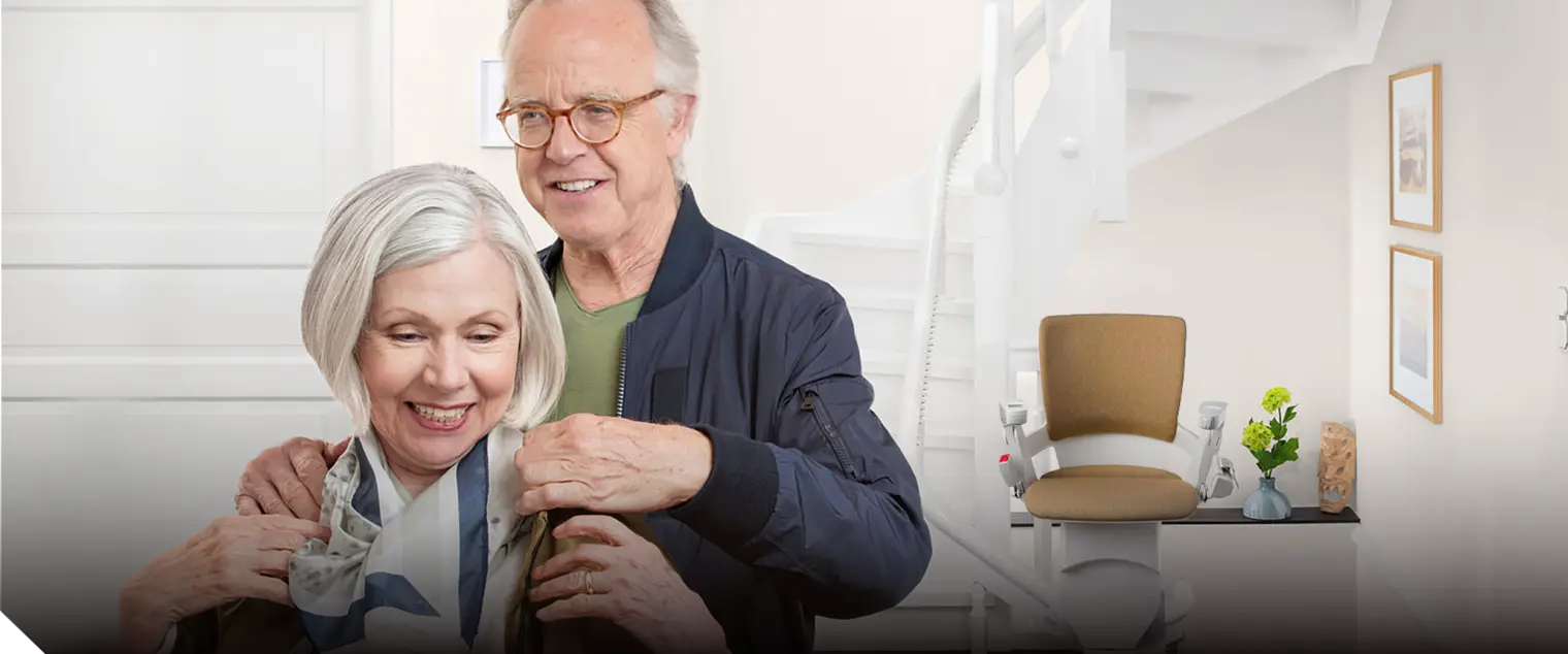 header-start.png Lächelndes älteres Paar vor einem Treppenlift
