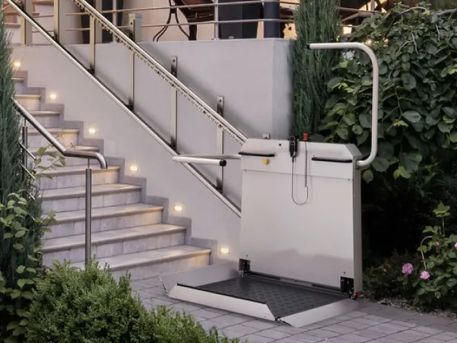 markenteaser-sanitrans.png Plattformlift für Rollstuhlfahrer von sani-trans am Ende einer beleuchteten Außentreppe