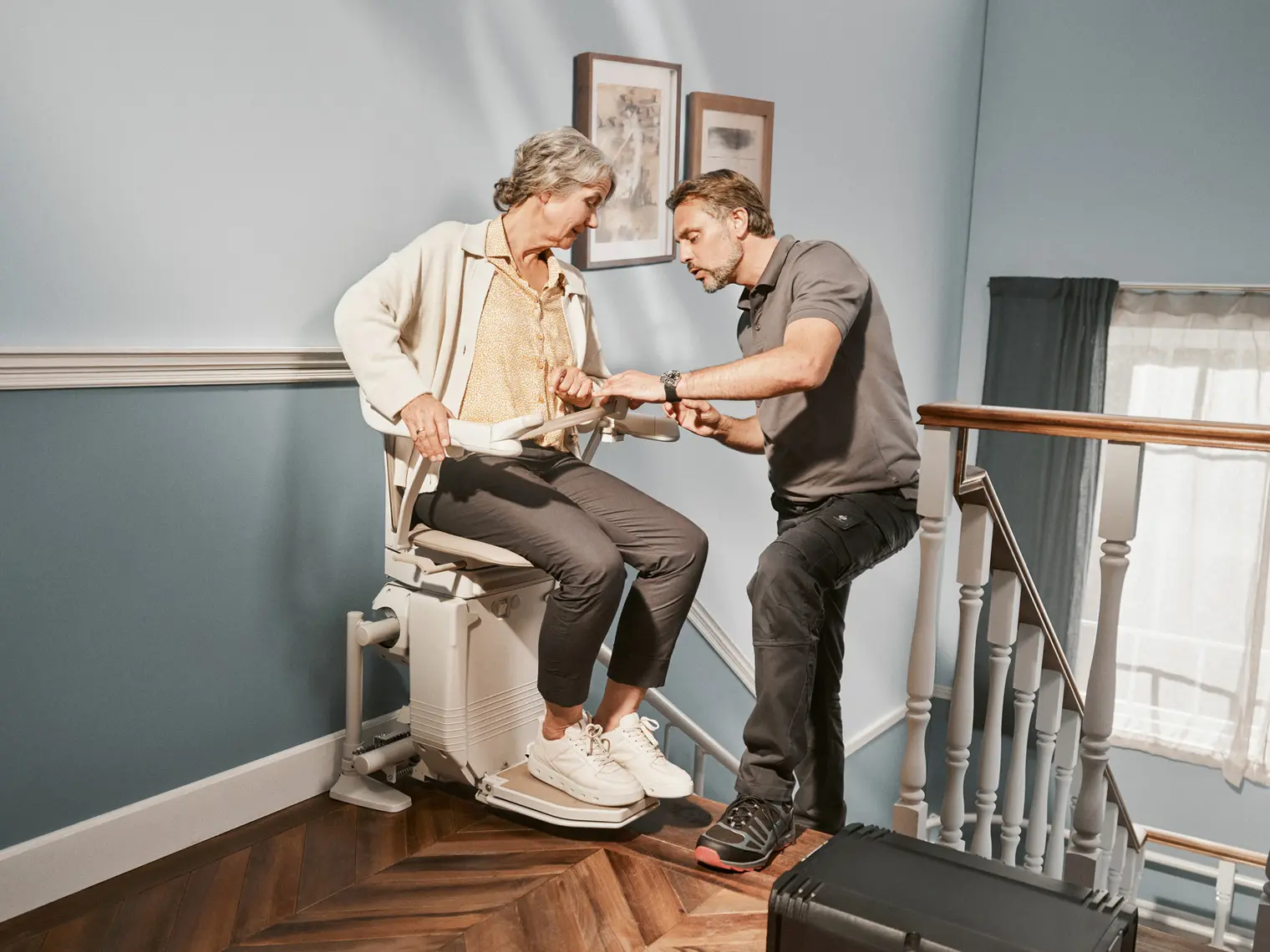 Ein Techniker erklärt einer Kundin die Funktionsweise ihres Treppenlifts