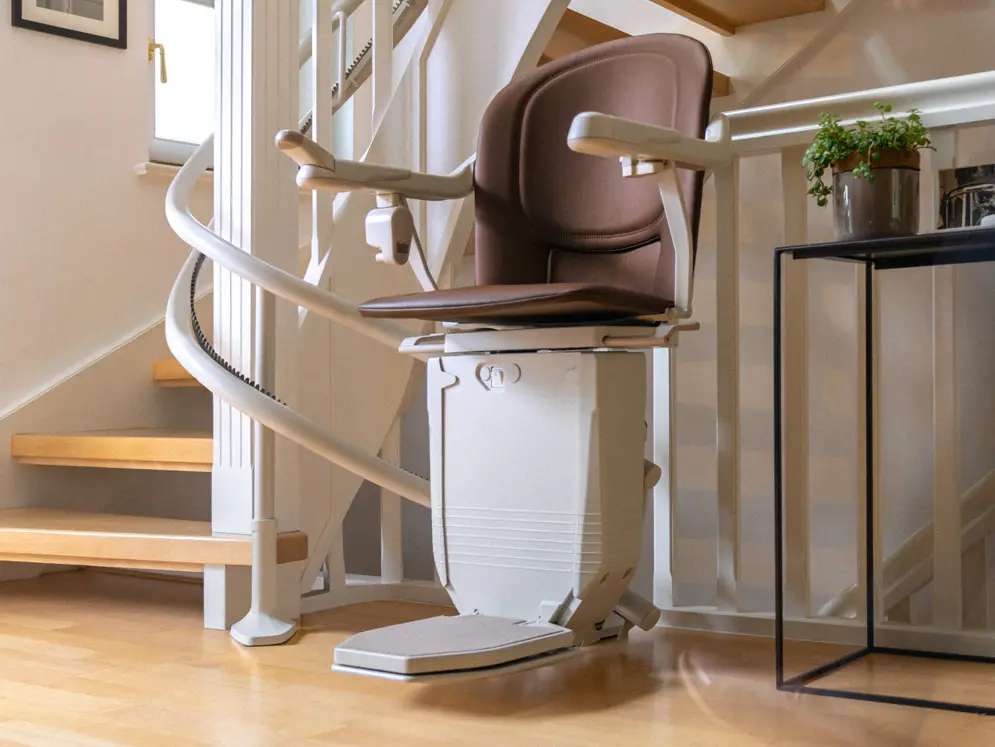 Ein Sitzlift mit braunem Polster an einer kurvigen Treppe