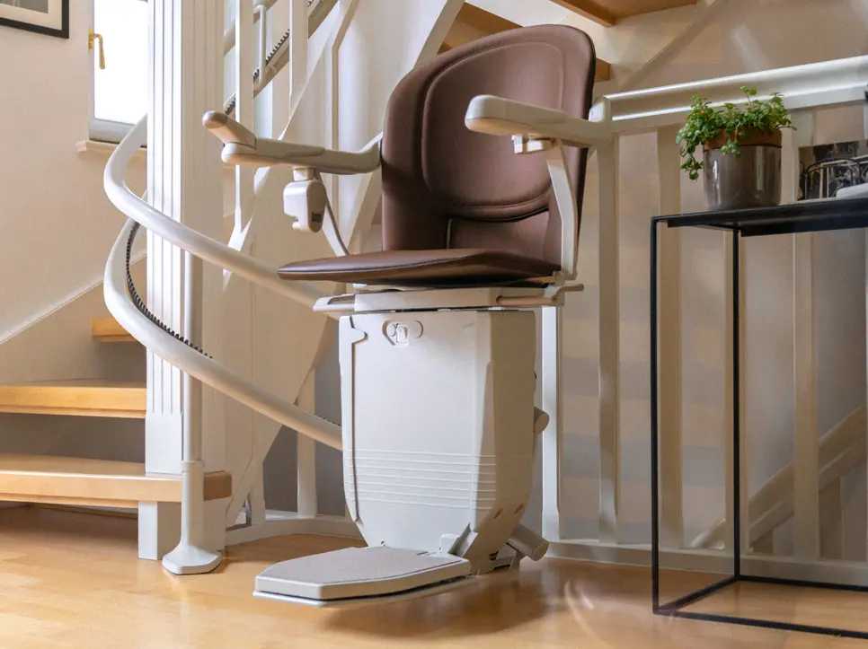 Ein Sitzlift mit braunem Polster an einer kurvigen Treppe