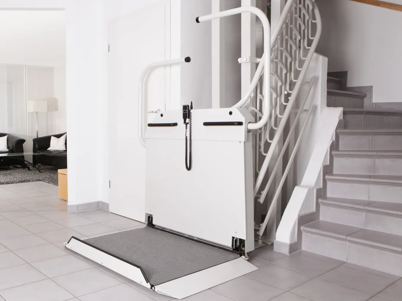 Ein weißer Rollstuhllift parkt am unteren Ende einer Treppe