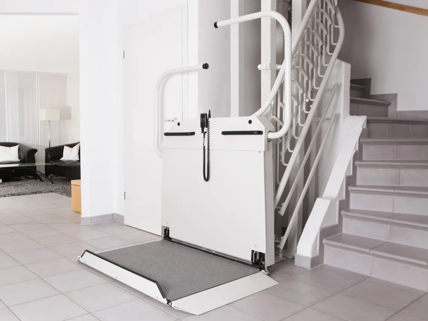 Ein weißer Rollstuhllift parkt am unteren Ende einer Treppe