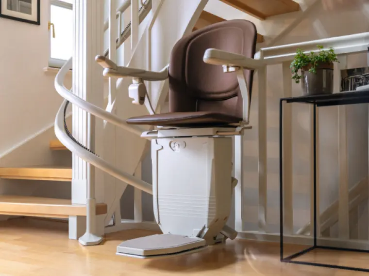 homelift-5.png Ein Sitzlift mit braunem Polster an einer kurvigen Treppe
