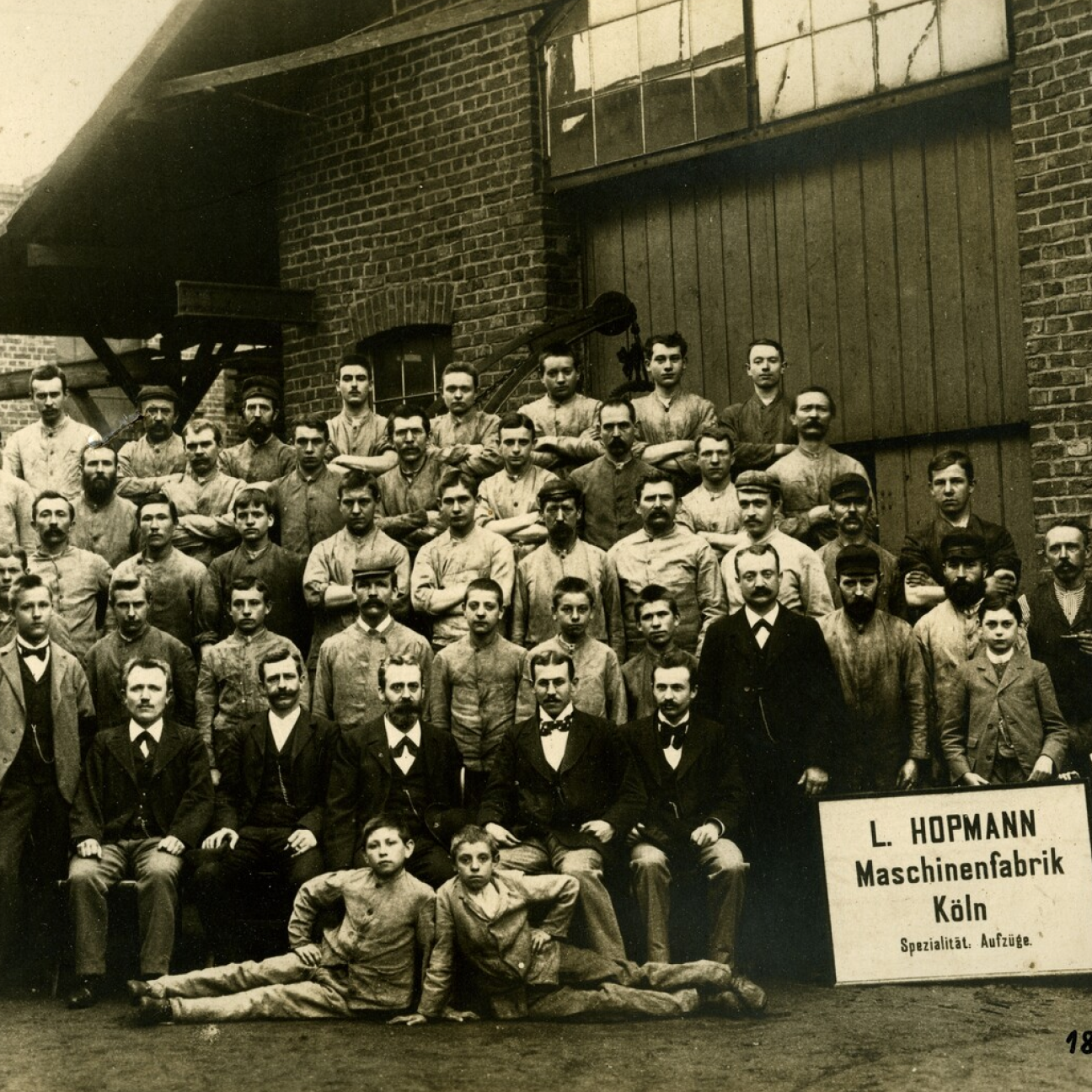 tab-vertikal-tradition.png Alte Sepia-Fotografie der Mitarbeiter der L.Hopmann Maschinenfabrik Köln