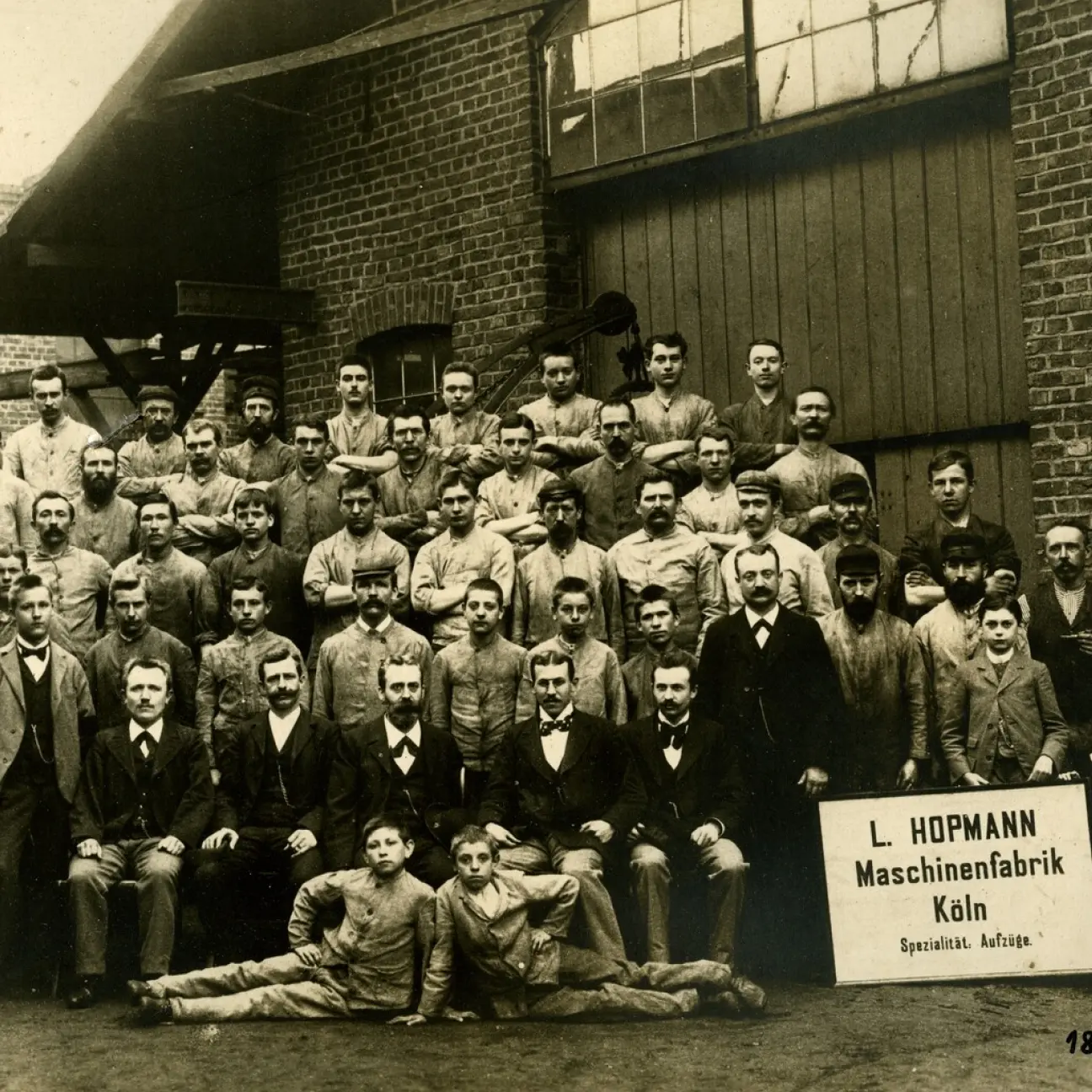 tab-vertikal-tradition.png Alte Sepia-Fotografie der Mitarbeiter der L.Hopmann Maschinenfabrik Köln