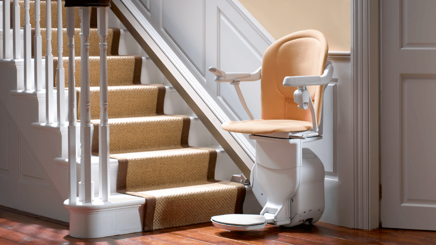 markenteaser-der-treppenlift.png Treppenlift mit apricot-farbenem Polster am Fuße einer geraden Treppe