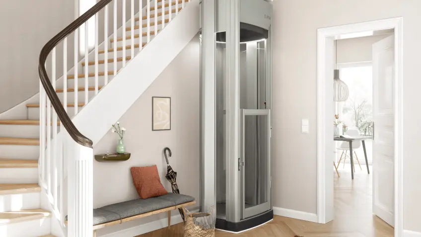 markenteaser-lifton.png Heller Eingangsbereich eines Wohnhauses mit einer weißen Holztreppe auf der linken Seite, darunter eine schmale Sitzbank mit grauem Polster, Kissen und einem Regenschirm. Daneben steht ein kompakter, verglaster Plattformlift in einem schmalen Schacht. Rechts führt eine offene Tür in einen freundlichen Essbereich mit Tisch und Stühlen; der Boden ist mit hellem Parkett ausgelegt.