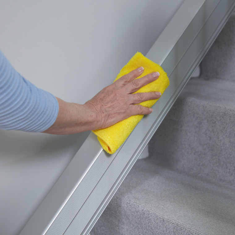 faq-reinigung.png Frau wischt Treppenlift-Schiene mit einem Tuch ab